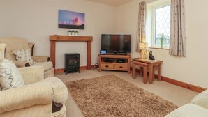 Una sala de estar con chimenea, televisor, sofá y una ventana con cortinas.