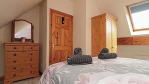 Un dormitorio con cama, cómoda, armario, espejo y tragaluz.