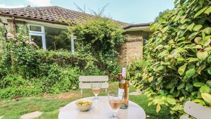 A garden patio with a table set for two, a bottle of wine, and a bowl of olives. - Little Yaffle (Dover)