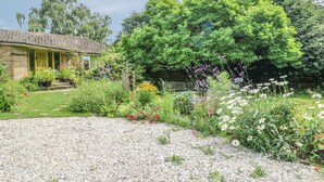 A garden with a variety of plants and flowers, a gravel path, and a house with a yellow door. - Little Yaffle (Dover)