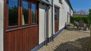 A house with large windows, a gravel driveway, and outdoor furniture. - The Croft (Holsworthy)
