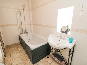 Une salle de bain avec une baignoire, un lavabo et un miroir.