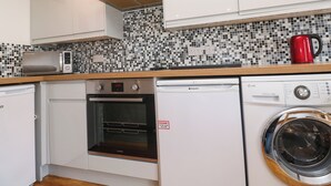 Une cuisine compacte équipée d’un four à micro-ondes, d’un four, d’un lave-vaisselle et d’un lave-linge.