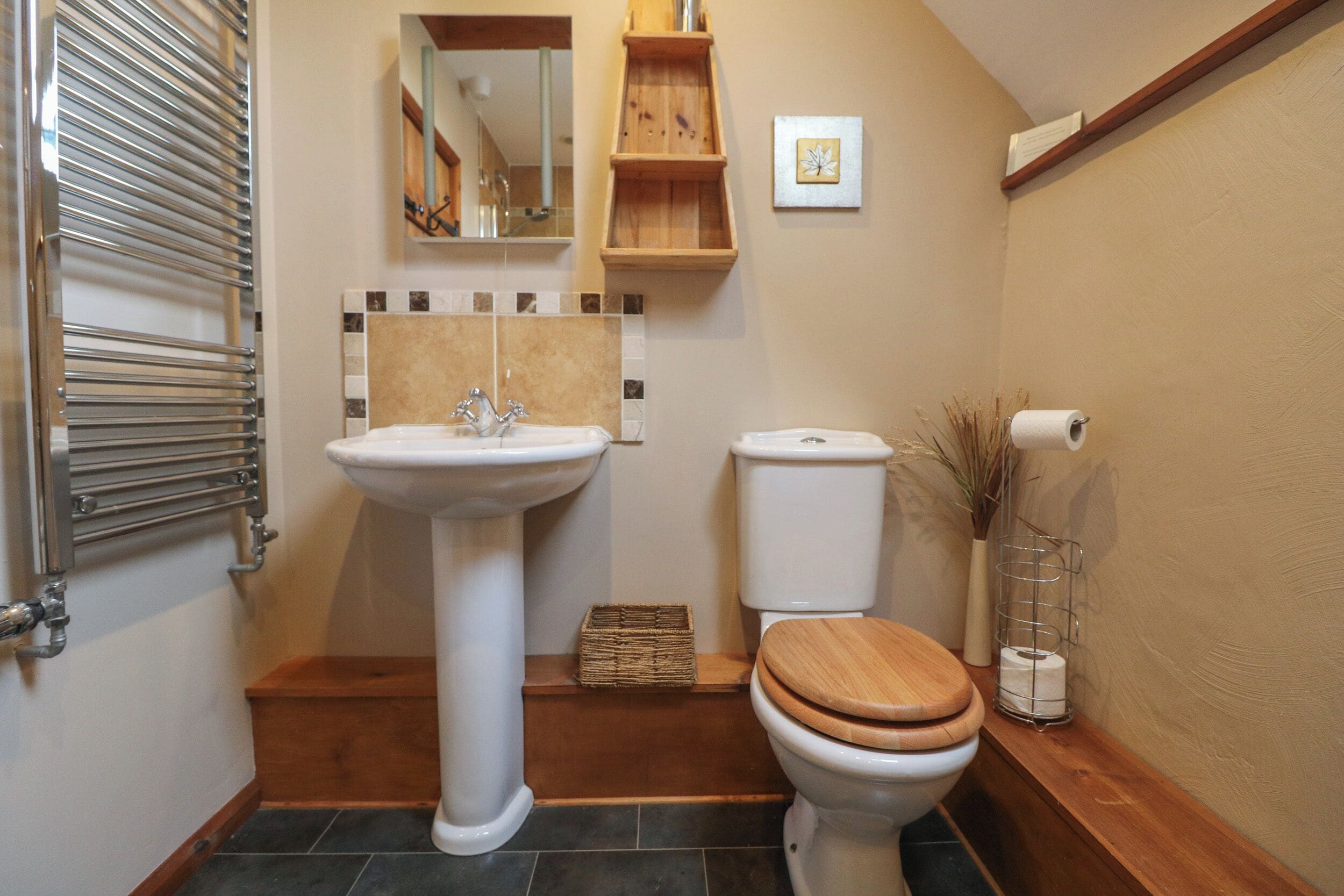 Un bagno con lavandino, WC e ripiano in legno.