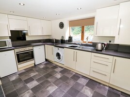 A modern kitchen with white cabinets, a built-in oven, a dishwasher, a washing machine, and a sink.