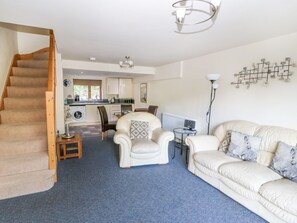A spacious living area with a staircase, a dining table with chairs, a sofa, and a kitchen in the background. - Hove Wood View (Hebden Bridge)