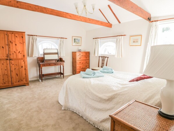 Un dormitorio con una cama grande, un armario de madera, un escritorio y un aparador.