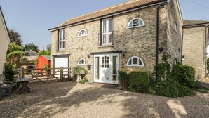 A two-story stone house with a gravel driveway and a wooden gate. - Stable Cottage (Sudbury)