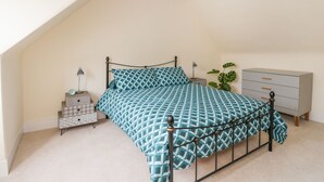 A bedroom with a bed, bedside tables, a dresser, and a plant. - Westwood (Ballater)