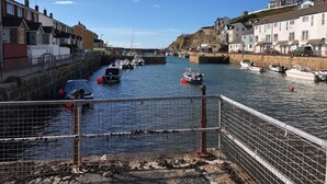 Un canal estrecho con barcos amarrados a ambos lados, bordeado por edificios residenciales y un puente al fondo.