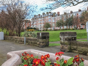 Stroll through a serene urban park surrounded by traditional townhouses and vibrant flowers.