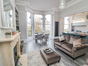 Cozy living area with a fireplace, sofa, and dining set, offering a view of the outside through large windows.
