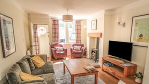 A cozy living room with a sofa, armchairs, a coffee table, a TV, and a wood-burning stove. - Clevelyn (Saltburn-by-the-Sea)