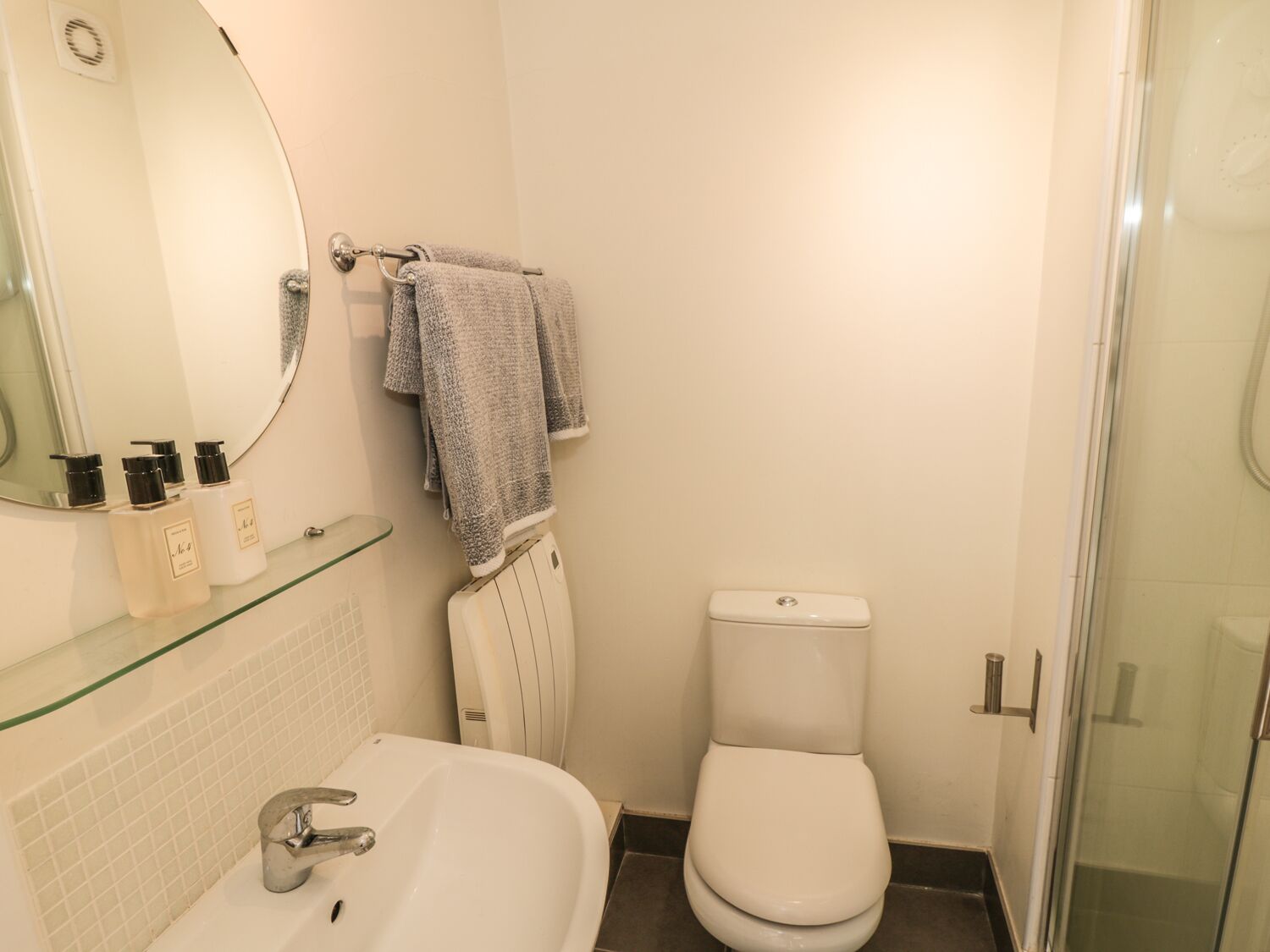Un baño con lavamanos blanco, inodoro y cabina de ducha de cristal.