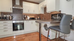 A modern kitchen with a built-in oven, microwave, and washing machine. - The Smithy (Bodmin)