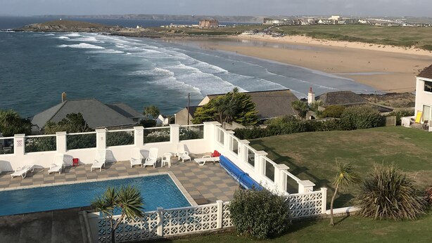 Ein Poolbereich mit Liegestühlen und Blick auf Strand und Meer.
