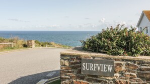 Eine Steinsäule mit einem Schild, das "SURFVIEW" zeigt, und Blick auf das Meer.