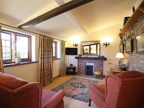 A cozy living room with a fireplace, two armchairs, a rug, and a stone wall. - Elephant Cottage (Bromyard)