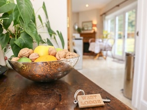 Een schaal met fruit en noten op een houten tafel, met een sleutelhanger met de tekst 'WEST LODGE' op de voorgrond.