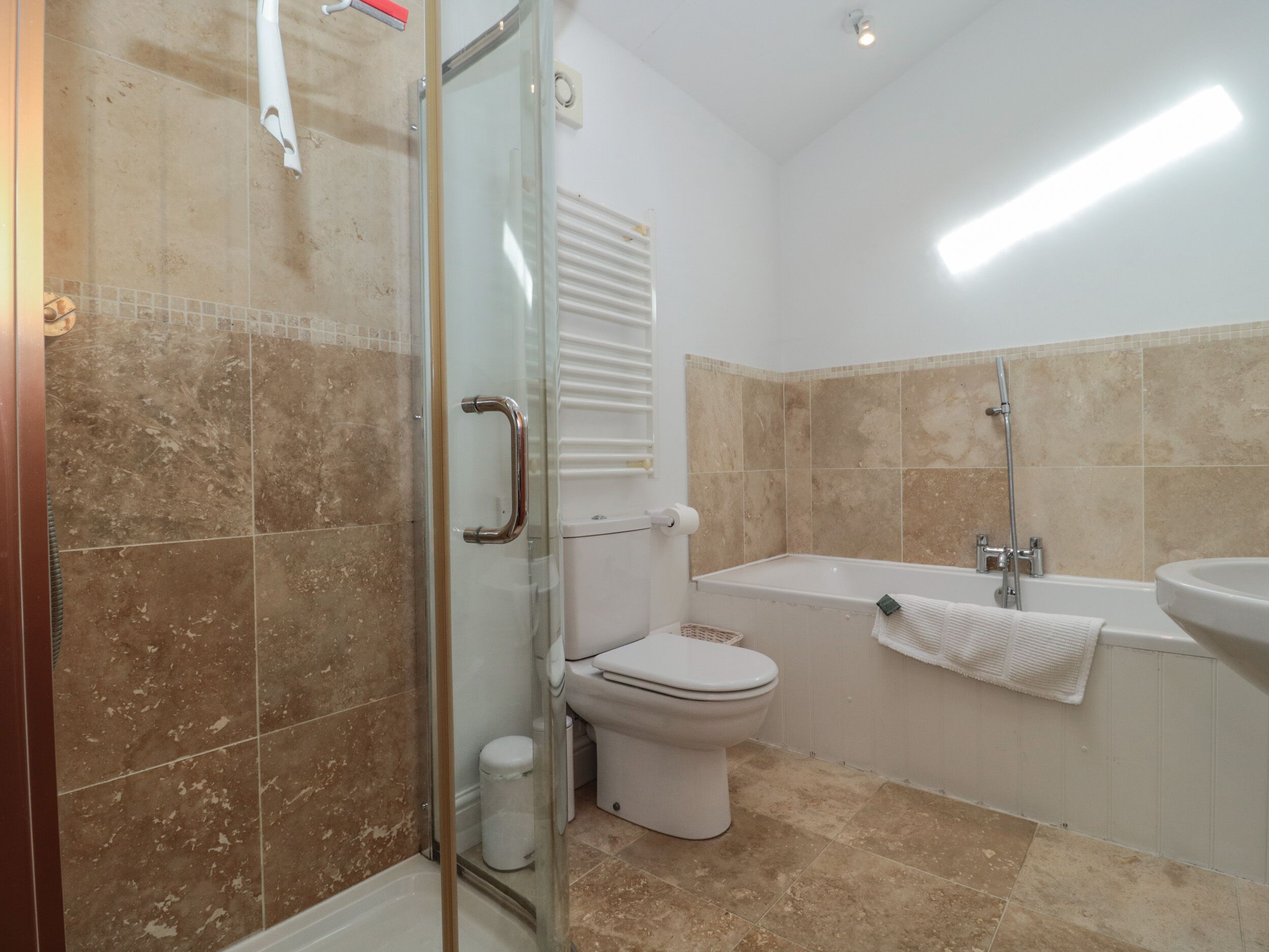 Un bagno con box doccia in vetro, un water, una vasca da bagno e un lavandino.