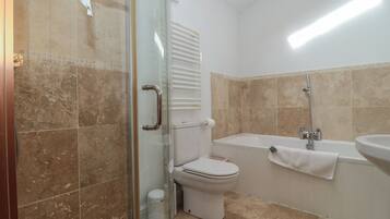 Un bagno con box doccia in vetro, un water, una vasca da bagno e un lavandino.