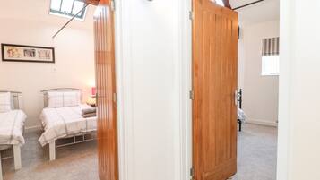 Een slaapkamer met twee bedden, een houten deur en een plafond met zichtbare balken.