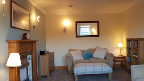 A cozy bedroom with a bed, bedside tables, a bookshelf, and a fireplace. - Sidhean Dubha Holiday Home (Portree)