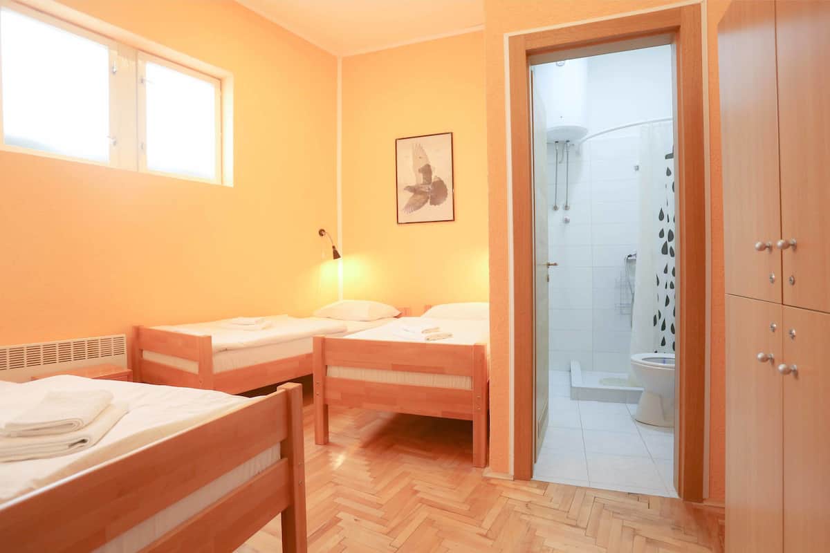 Un dormitorio con dos camas de madera, una ventana, un cuadro enmarcado y un armario de madera.