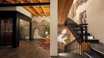 A modern interior with a wooden ceiling, a staircase with black railings, and a dining area with a table and chairs.
