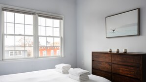 A bedroom with a bed, a dresser, a window, and a wall-mounted picture. - Giles Ave 6 Bedroom Gem (Jersey City)