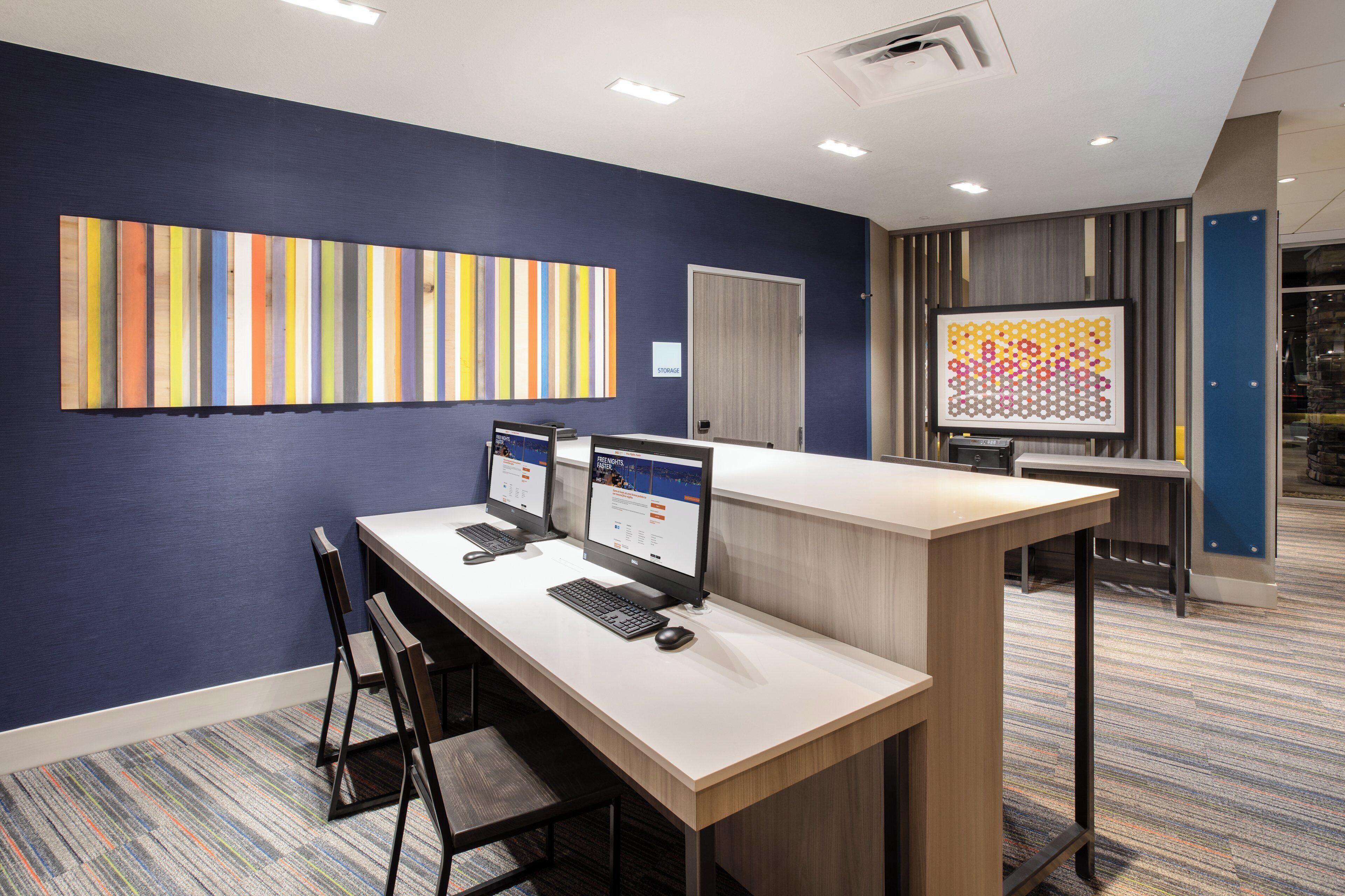 A modern office space with a long desk, two computers, and a chair.