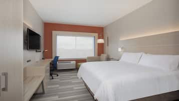 A hotel room with a bed, desk, chair, television, and a window.