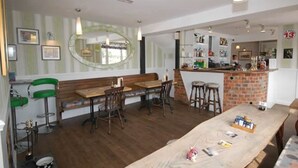 A restaurant with a long wooden table, bar stools, and a brick counter. - The Old Red Lion (Thame)