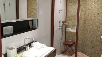 A bathroom with a vanity, sink, mirror, toilet, and shower enclosure.