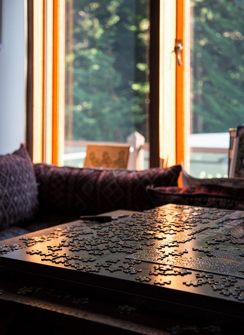 A puzzle on a table near a window with a view of trees.