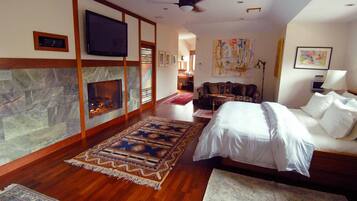 A spacious room with a fireplace, a bed, a TV, and a ceiling fan.