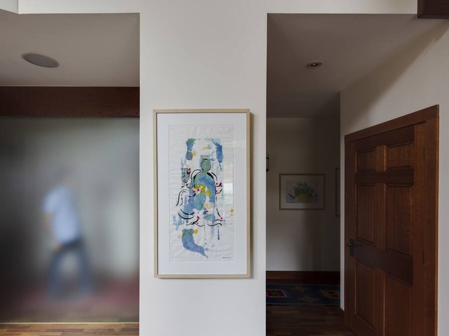 A hallway with a framed abstract painting on the wall, a wooden door, and a stone wall on one side.