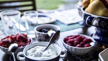 A table with bowls of yogurt and berries, a bowl of bread, and a cup of coffee.