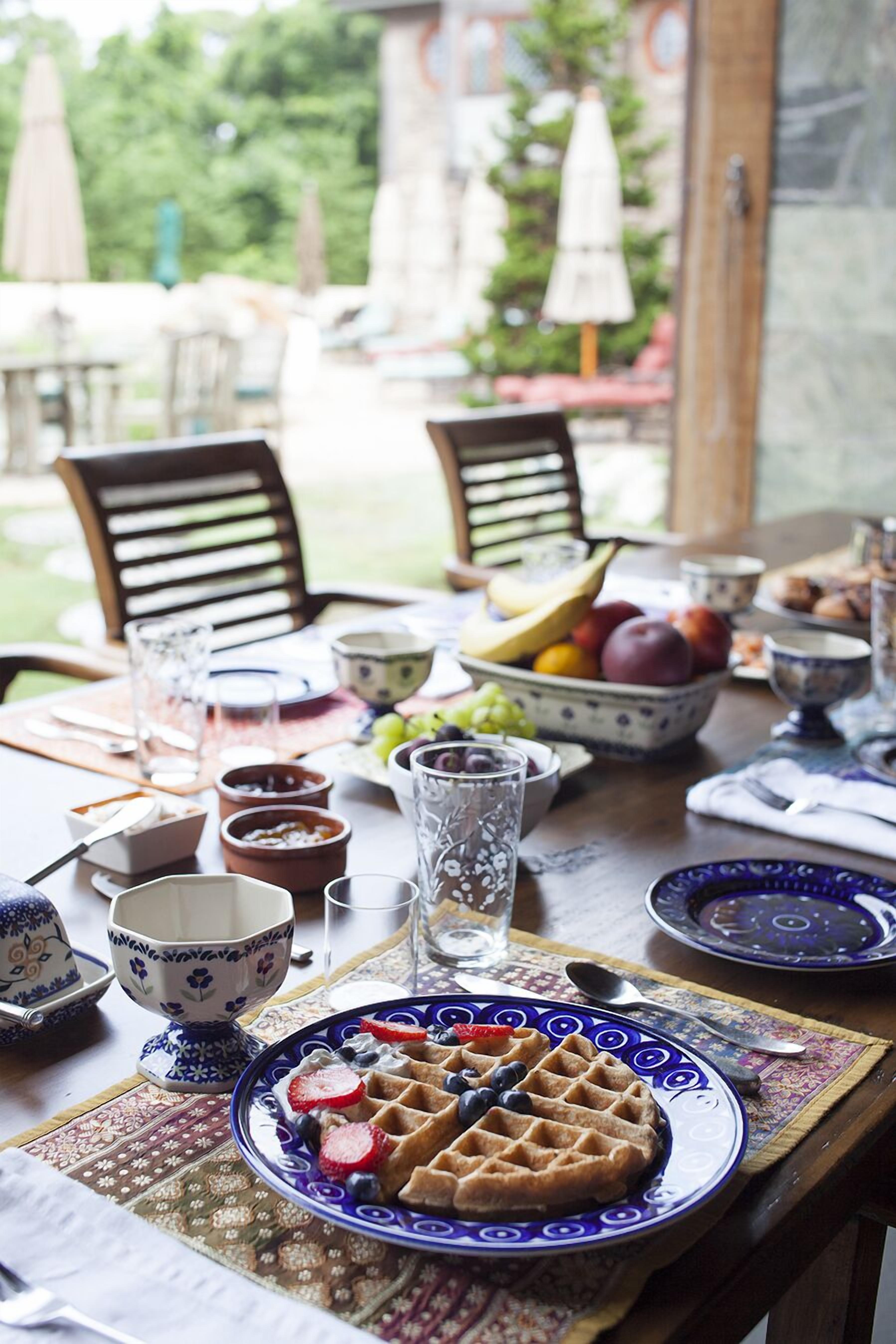A table set for breakfast with a waffle, fruit, and various bowls and cups.