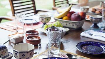 A table set for breakfast with a waffle, fruit, and various bowls and cups.