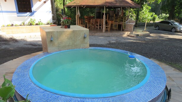 Una piscina circular con borde de azulejos azules, rodeada por una cubierta de madera.