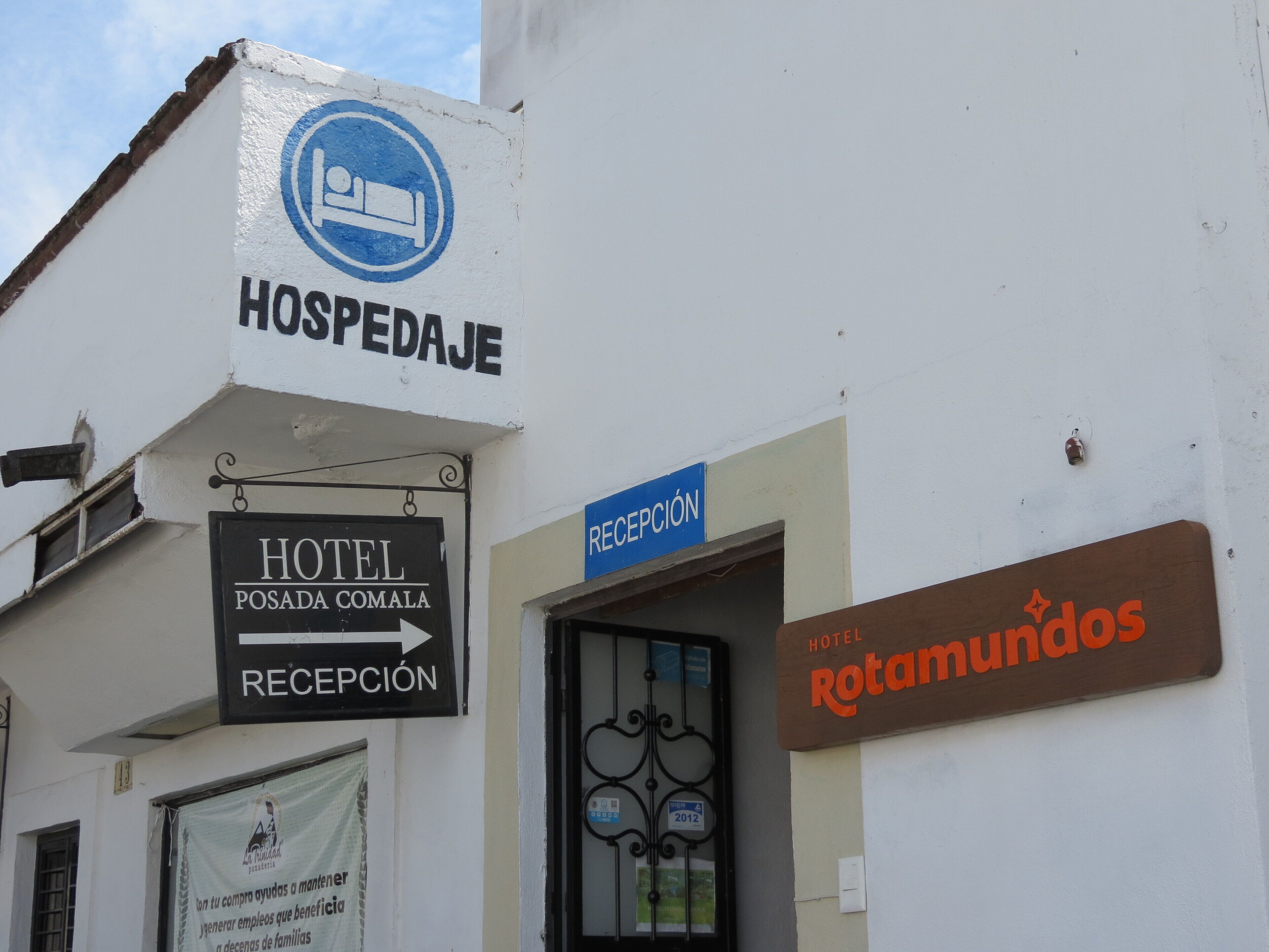 Un edificio con letreros que dicen 'HOSPEDAJE' y 'HOTEL POSADA COMALA', y una zona de recepción.