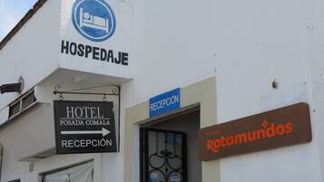 Un edificio con letreros que dicen 'HOSPEDAJE' y 'HOTEL POSADA COMALA', y una zona de recepción.