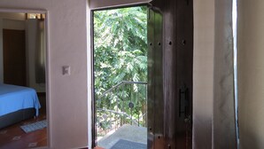 Una habitación con una cama, una puerta que da al exterior y vistas a zonas verdes.