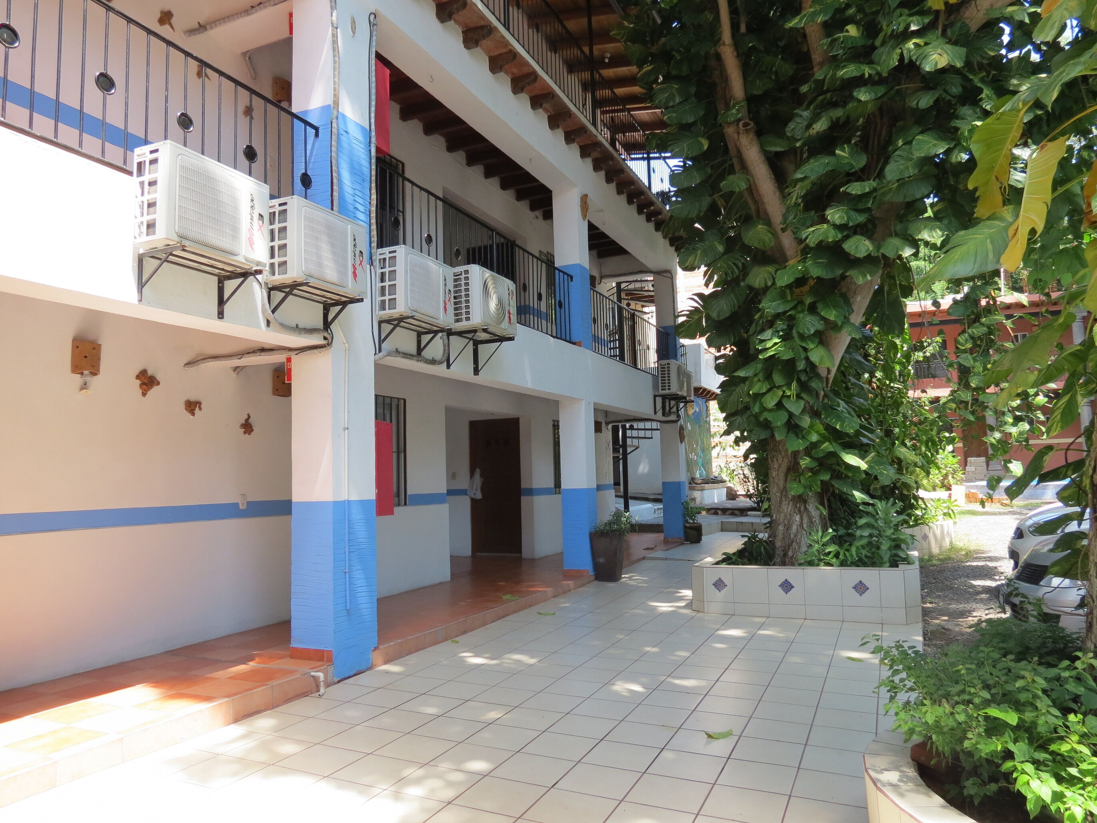 A multi-story building with balconies, air conditioning units, and a tiled patio area.