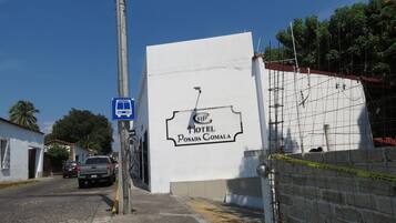 Un edificio blanco con un cartel que dice 'Hotel Posada Comala' y una señal de parada de autobús azul.