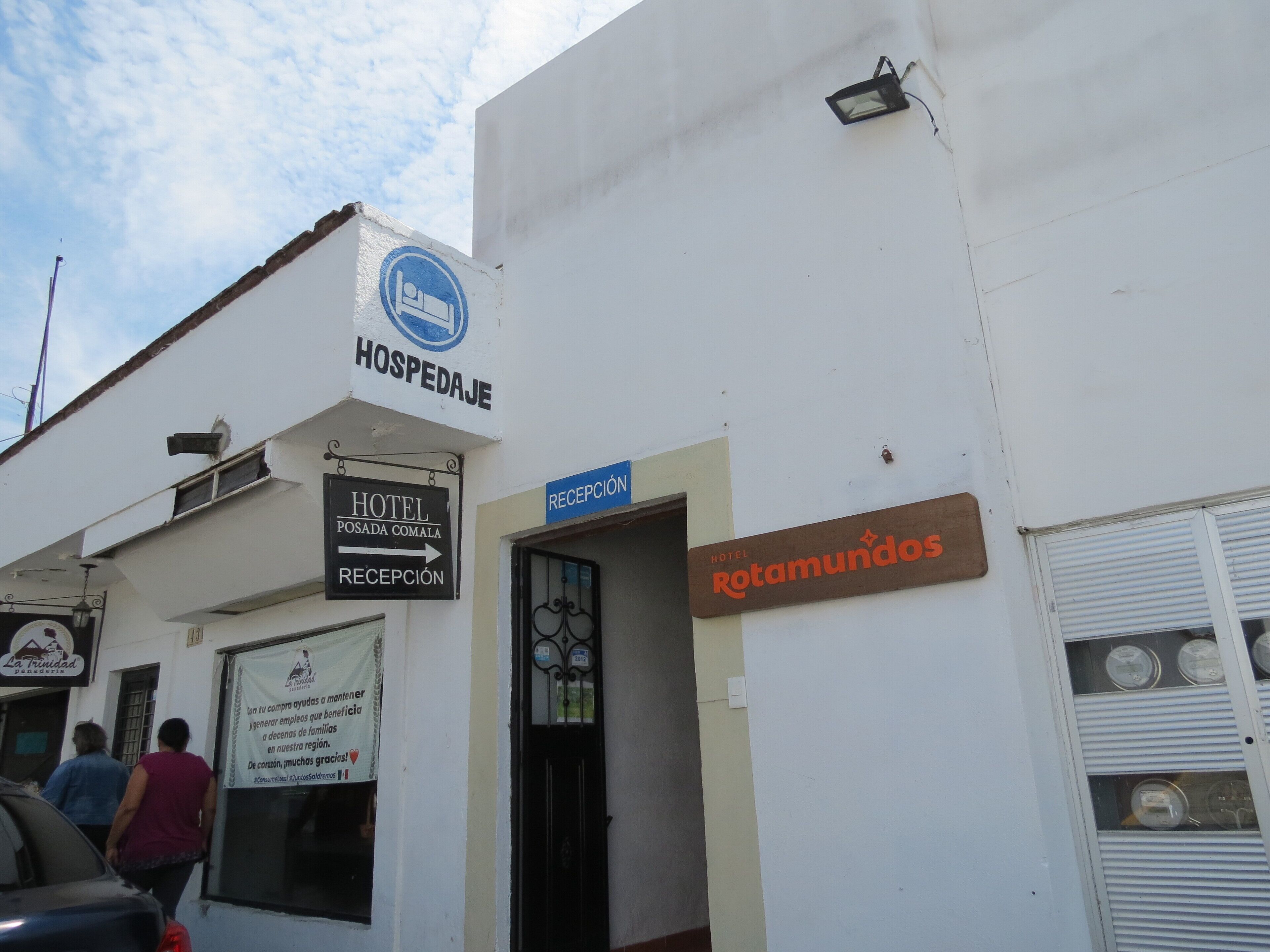 Un edificio con letreros que indican 'HOSPEDAGE' y 'HOTEL POSADA COMALA', y una zona de recepción.