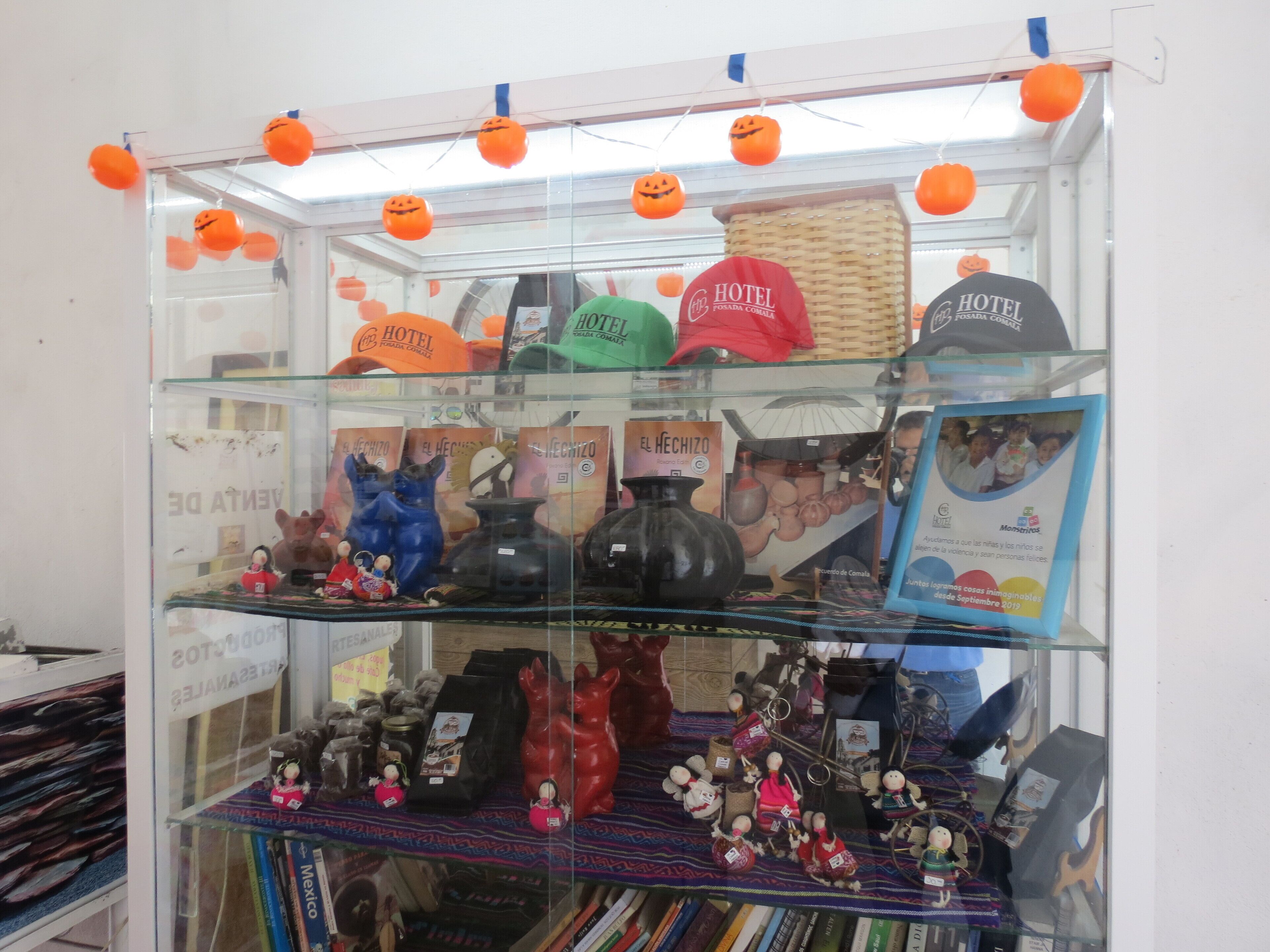 A display of various souvenirs and items, including hats and figurines, in a glass case.