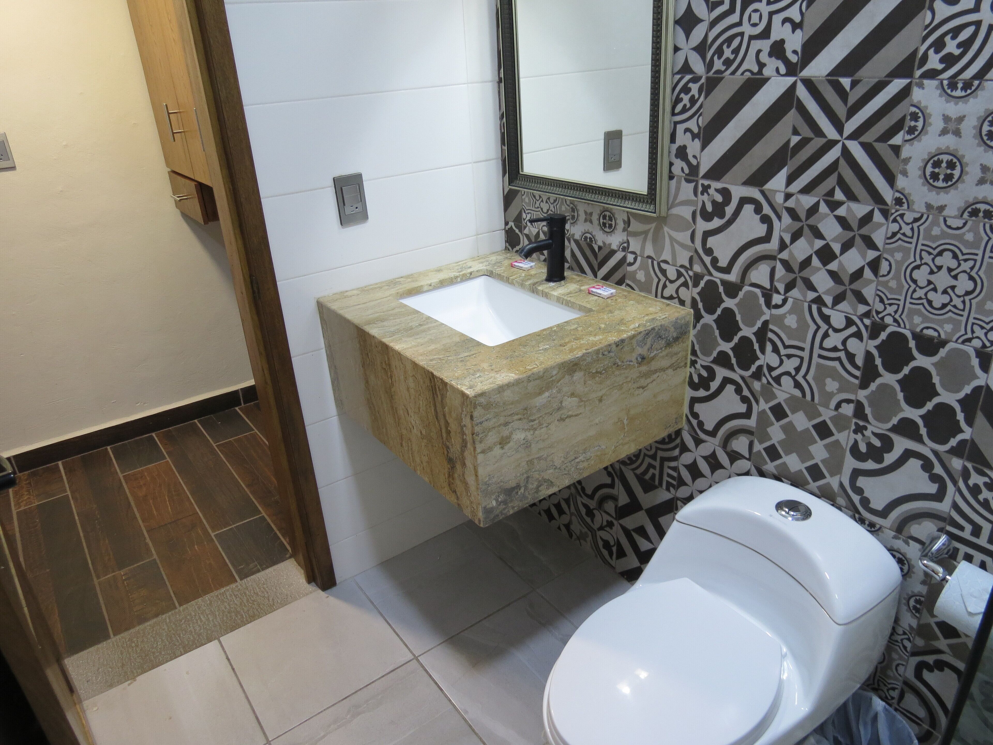 Ein Badezimmer mit Marmorwaschbecken, Toilette und gemusterten Fliesen.