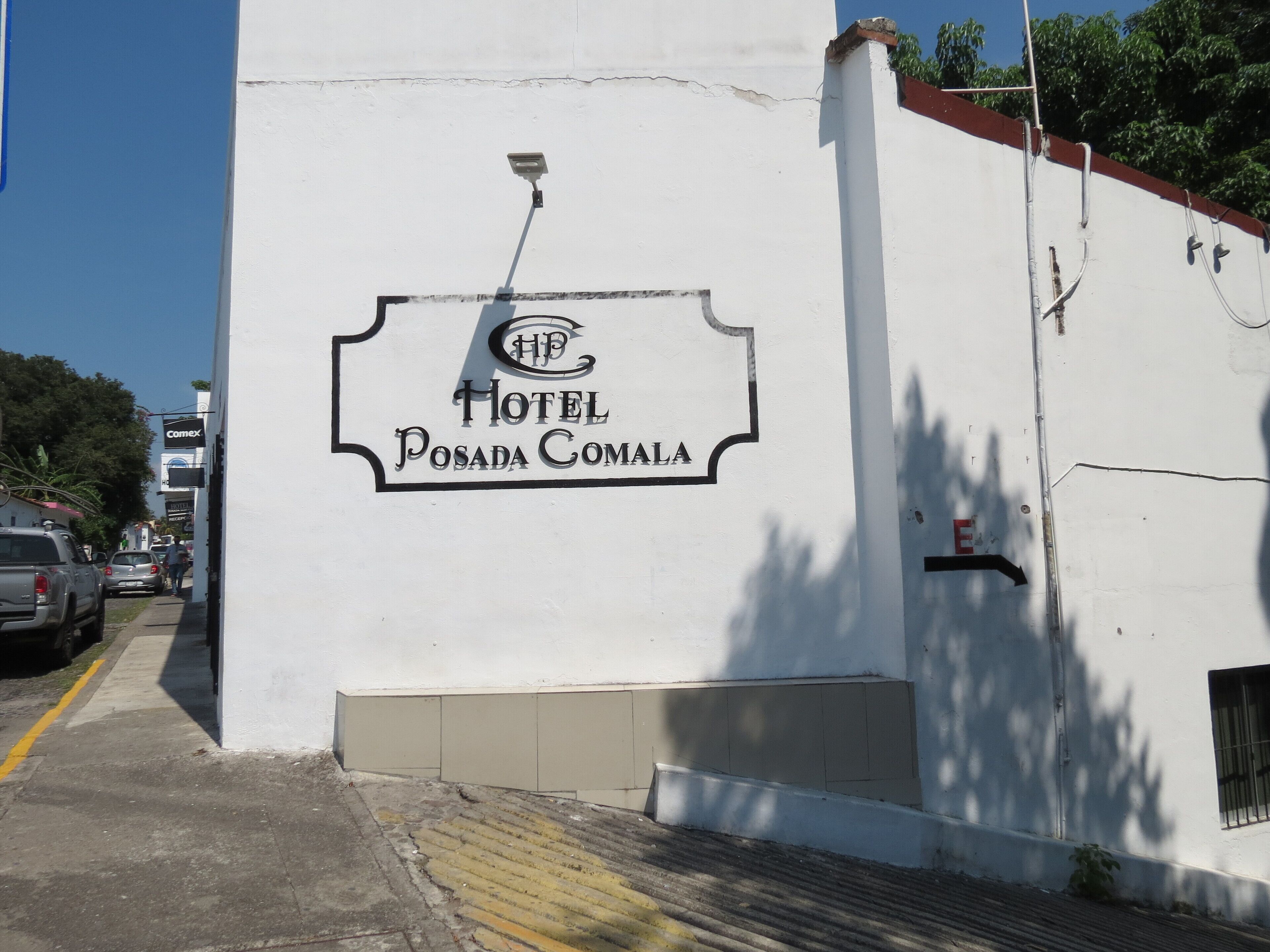 Edifici blanc amb un senyal que mostra 'Hotel Posada Comala', incloent un logotip i el nom.